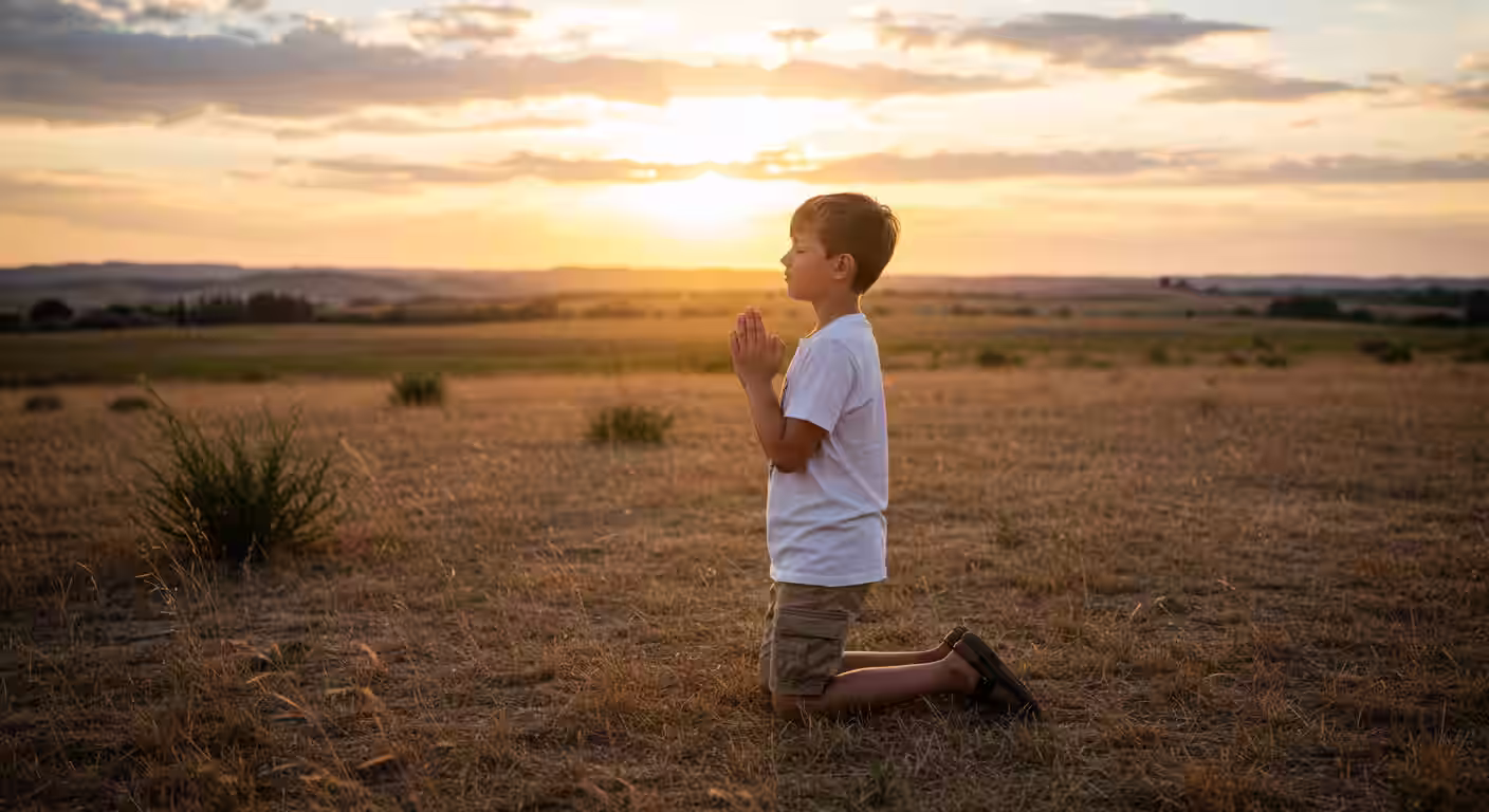 Jovem ajoelhado em oração ao pôr do sol